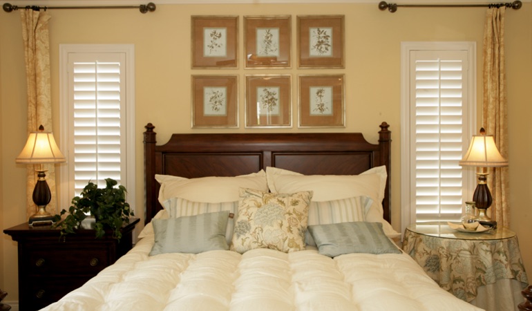 Beige bedroom with white plantation shutters covering windows in Boston